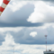 An airport scene with a windsock prominently displayed against a cloudy sky